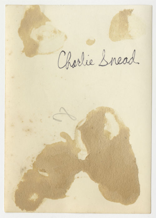 Charles "Charlie" Snead standing behind a vehicle. Verso
