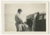 Unidentified individual standing beside a car