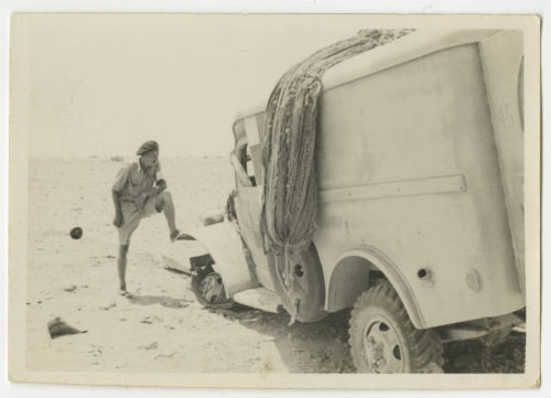 Wayne McMeekan with ambulance damaged by a land mine. Recto