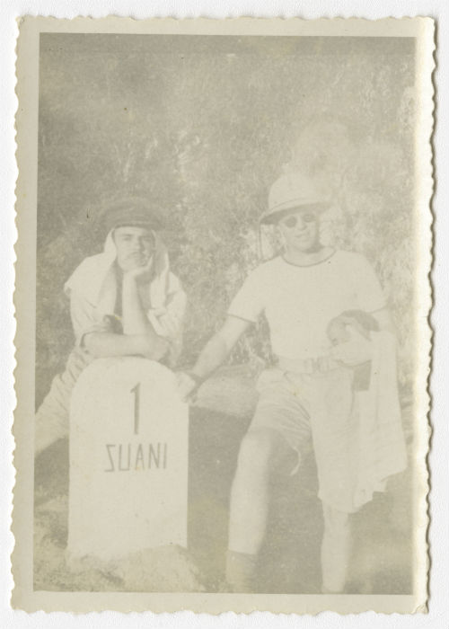 Unidentified individual and Bayard "Newport Nellie" King leaning against a milestone near Al-Swani