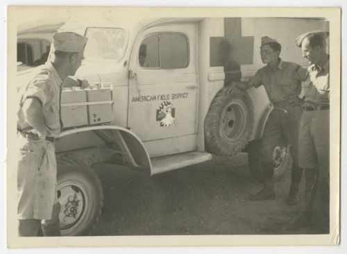 William "Bill" Gosline (hand on tire) and Samuel "Sam" Hobbs observing the new insignia. Recto